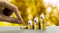 Property investment concept. Hand holding coin over a small house model on stack of coins. Depicts using real estate turns into Royalty Free Stock Photo