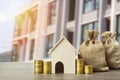 Property investment concept. A small house model with stack of coins and money bag on table. Depicts using real estate turns into Royalty Free Stock Photo