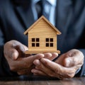 Property safeguarded Businessman protects wooden home model with his hand Royalty Free Stock Photo