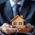 Property safeguarded Businessman protects wooden home model with his hand Royalty Free Stock Photo