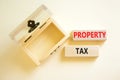 Property tax symbol. Concept words Property tax on wooden blocks. Beautiful white table white background. Wooden empthy chest.