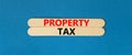 Property tax symbol. Concept words Property tax on wooden stick. Beautiful blue table blue background. Business and property tax