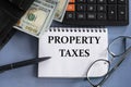 PROPERTY TAXES - words in a notebook against the background of money, glasses and calculator