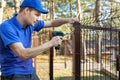 Property territory fencing - man screws metal fence panel