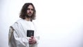 Prophet in white robe holding Bible, praying to God with humility, devotion