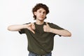 Pros or cons. Young indecisive man shows thumbs up and thumbs down, review smth, feedback, standing in tshirt over white Royalty Free Stock Photo