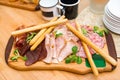 Prosciutto breadsticks with variety cured meat on wooden board