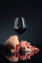 Prosciutto with ciabatta, red wine and thyme on a black background Royalty Free Stock Photo