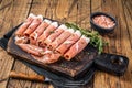 Prosciutto crudo Dry cured parma ham on a wooden cutting board with thyme. wooden background. Top View