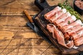 Prosciutto crudo Dry cured parma ham on a wooden cutting board with thyme. wooden background. Top View. Copy space