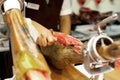 Prosciutto or jamon serrano. Close up on hands of a chef cutting traditional Italian Spanish ham. Slicing prepared hamon Royalty Free Stock Photo