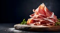 Prosciutto. Stack of Prosciutto ham slices on wooden board on dark background, copy space. Italian charcuteries board with cured