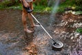 Prospector man with metal detector searches for lost gold treasure over water on the Hassayampa River in Kirkland, Arizona, USA