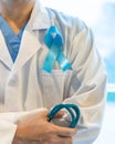 Prostate cancer blue awareness ribbon for men health in November with light blue bow color on medical doctor in clinical lab gown