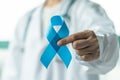 Prostate cancer blue awareness ribbon for men health in November with light blue bow color on medical doctorÃ¢â¬â¢s hand in clinical