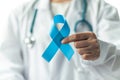 Prostate cancer blue awareness ribbon for men health in November with light blue bow color on medical doctorÃ¢â¬â¢s hand in clinical