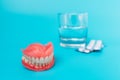 A prosthesis and a glass with a solution. Dental prosthesis care. Full removable plastic denture of the jaws. Upper and lower jaws Royalty Free Stock Photo