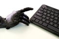 Black robot hands and computer keyboard on a light table background. The prosthesis of a human hand raised his index finger to Royalty Free Stock Photo