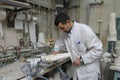 Worker applies special coating on wooden blank for further manufacturing prosthesis