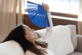 Prostrated young female fanning herself on couch suffering from heat