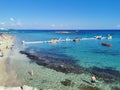 Protaras. Famagusta area. Cyprus. Fig Tree Bay Beach, small island opposite, people sunbathing and swimming on a sunny autumn day