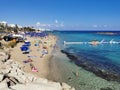 Protaras. Famagusta area. Cyprus. Fig Tree Bay Beach, small island opposite, people sunbathing and swimming on a sunny autumn day