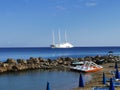 Sandy beach in a bay with sun loungers and catamarans, in the Mediterranean Sea the largest sailing yacht in the world, an eight-