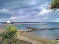 Sandy shore with a stone ridge, Kalamies beach, the Church of St. Nicholas the Wonderworker against the backdrop of a dramatic sky Royalty Free Stock Photo