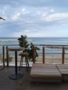 Protaras. Famagusta region. Cyprus. Cafe next to the beach. Tables and bar stools made of sawn wood and low striped mattresses Royalty Free Stock Photo