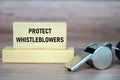 Protect Whistleblowers text on wooden blocks with whistle background Royalty Free Stock Photo