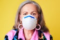 Protect your golden years at all costs. Portrait of a quirky senior woman wearing a N95 face mask against a yellow