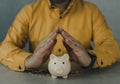 Protect your money concept. Man protected a piggy bank by hands Royalty Free Stock Photo