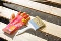 Protecting gloves and paintbrush on wooden surface. Carpentry, wood treatment, hard at work, home improvement, do-it-yourself