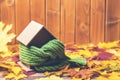 Protecting and isolating house. Scarf around house model on wooden table. Small miniature of house in warm scarf on autumn leaves Royalty Free Stock Photo
