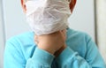 A diseased child drags his hand into his throat . Kids in protective mask on his face coughs, holding hands by the neck, sore