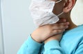 A diseased child drags his hand into his throat . Kids in protective mask on his face coughs, holding hands by the neck, sore