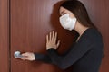 Protection against the spread of coronavirus. A young woman in an antibacterial mask knocks on a locked door, wants to get out on Royalty Free Stock Photo