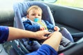 Protection in the car. woman is fastening security belt to child, who is sitting in safety car seat Royalty Free Stock Photo