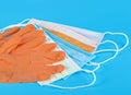 Protection concept - pair of orange latex medical gloves and colored surgical masks on blue background Royalty Free Stock Photo