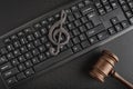 Protection of music as intellectual property. Treble clef on the keyboard next to the wooden gavel on black background. Music Royalty Free Stock Photo