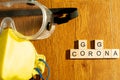 Protective eyewear and yellow mask with outlet valve with wooden blocks spelling out go corona go on a wood floor