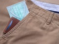 Protective face mask and money clip in pocket brown long pants.