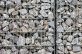 Protective gabions with grey broken stones behind grid as solid fence and solid wall and decorative element in gardens with rough