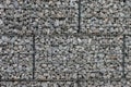 Protective gabions with grey broken stones behind grid as solid fence and solid wall and decorative element in gardens with rough