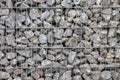 Protective gabions with grey broken stones behind grid as solid fence and solid wall and decorative element in gardens with rough