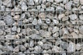 Protective gabions with grey broken stones behind grid as solid fence and solid wall and decorative element in gardens with rough