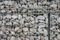 Protective gabions with grey broken stones behind grid as solid fence and solid wall and decorative element in gardens with rough