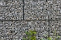 Protective gabions with grey broken stones behind grid as solid fence and solid wall and decorative element in gardens with rough