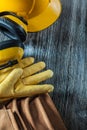 Protective gloves building helmet earmuffs tool belt on wooden b