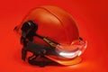 Protective goggles for eyes and construction helmet for head with earmuffs and headlamp on a red background. Construction tool and Royalty Free Stock Photo